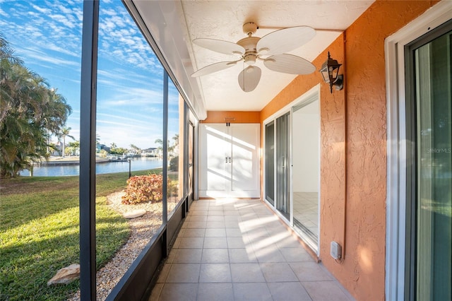 unfurnished sunroom featuring a water view and ceiling fan