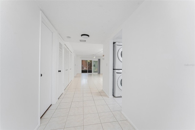 hallway featuring light tile patterned flooring and stacked washer and clothes dryer