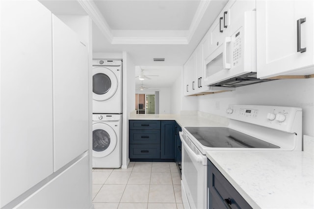 kitchen with light tile patterned floors, white appliances, ceiling fan, stacked washer / dryer, and white cabinets