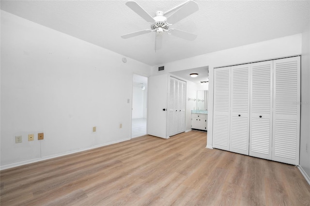 unfurnished bedroom with ceiling fan, a textured ceiling, light wood-type flooring, and ensuite bath