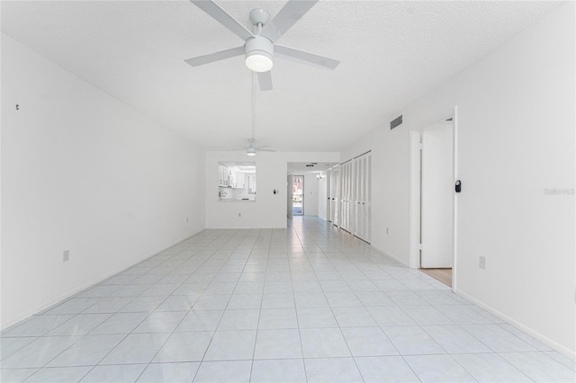 spare room with ceiling fan, a textured ceiling, and light tile patterned floors