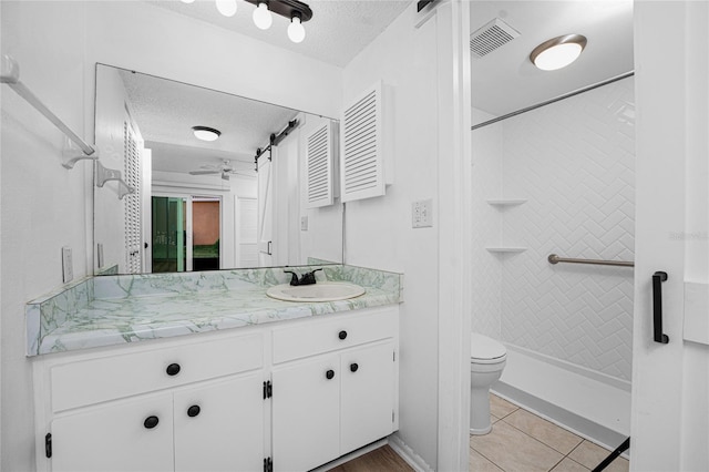 bathroom featuring a tile shower, tile patterned flooring, vanity, toilet, and a textured ceiling