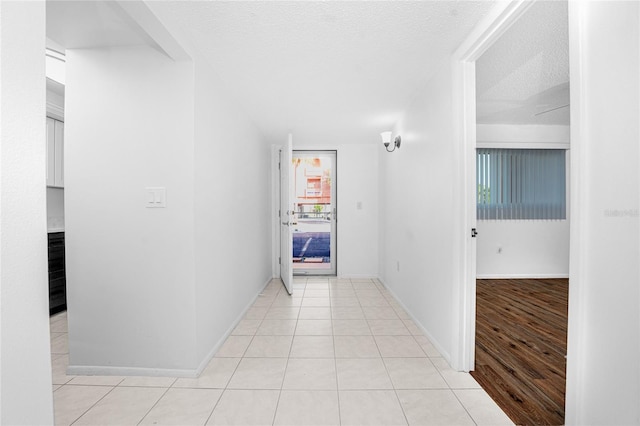 hallway featuring a textured ceiling and light tile patterned floors