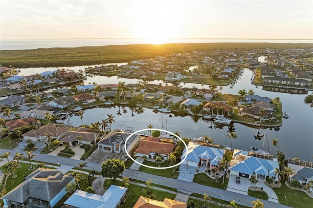 aerial view at dusk featuring a water view and a residential view