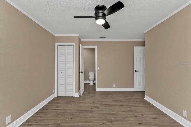 unfurnished bedroom featuring ceiling fan, hardwood / wood-style floors, ensuite bathroom, and ornamental molding