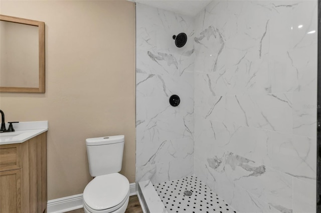 bathroom with hardwood / wood-style flooring, toilet, vanity, and a tile shower