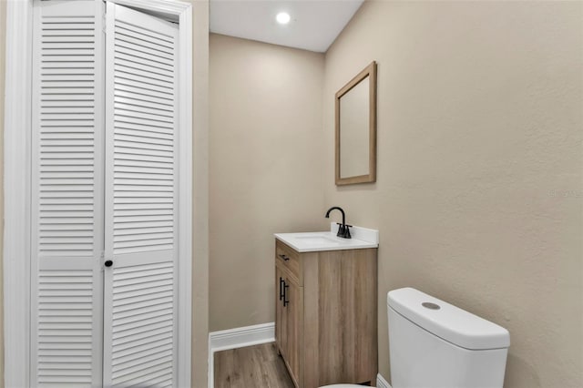 bathroom with wood-type flooring, toilet, and vanity