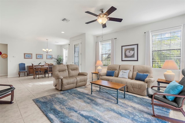 living room featuring light tile patterned floors, ceiling fan with notable chandelier, and a healthy amount of sunlight