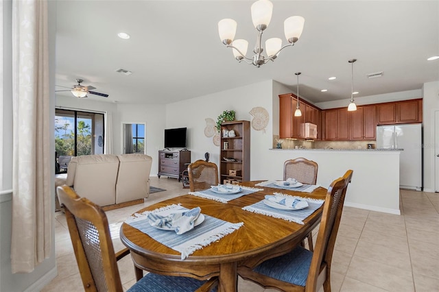 tiled dining space with ceiling fan with notable chandelier