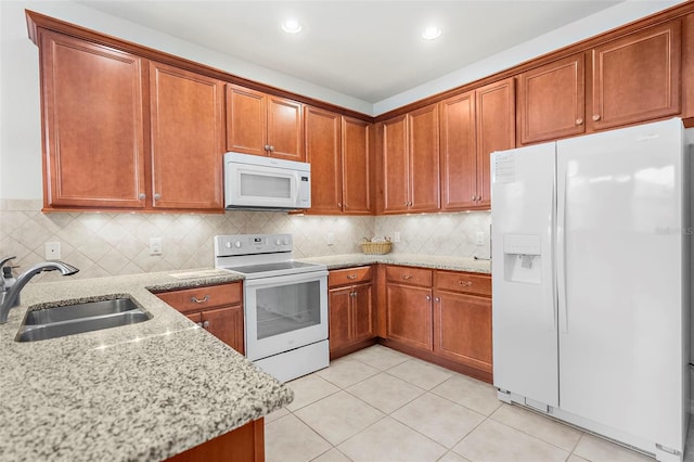 kitchen with tasteful backsplash, light stone countertops, sink, and white appliances