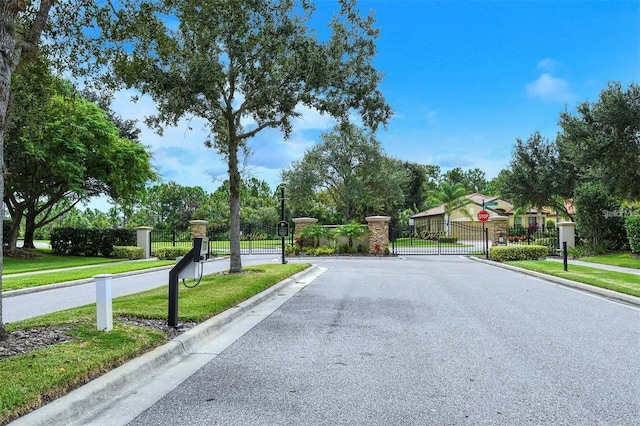 view of road with a gate, traffic signs, sidewalks, curbs, and a gated entry