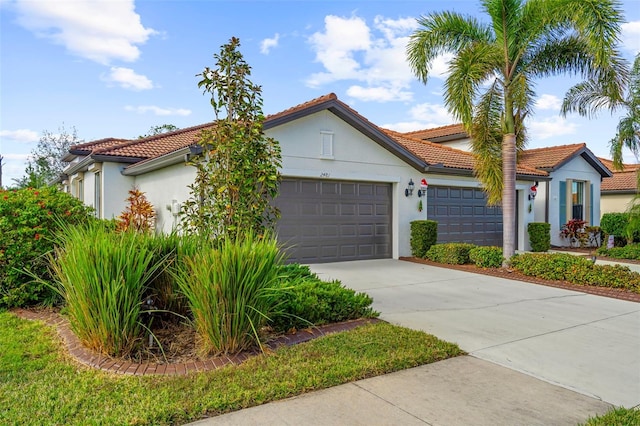 mediterranean / spanish-style house with concrete driveway, a tiled roof, a garage, and stucco siding