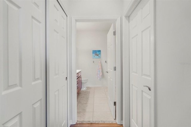 corridor featuring light tile patterned floors and baseboards