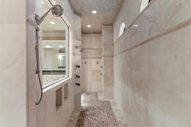 bathroom featuring tile patterned flooring, a tile shower, and tile walls