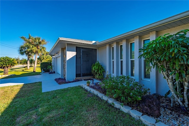 property entrance with a garage and a lawn