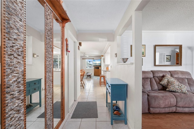 hall with a textured ceiling, crown molding, and light tile patterned flooring