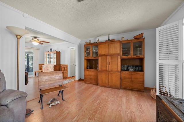 sitting room with a textured ceiling, light wood-type flooring, ceiling fan, and crown molding