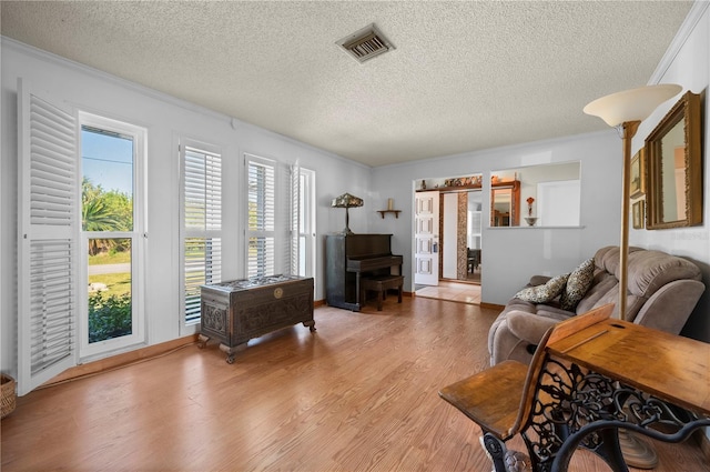 living room with ornamental molding, a textured ceiling, and light hardwood / wood-style flooring