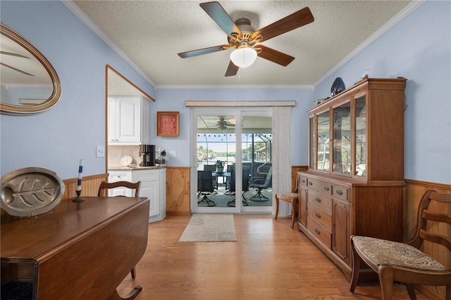 interior space with crown molding, wooden walls, a textured ceiling, and light wood-type flooring