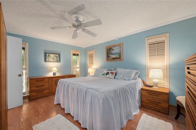 bedroom with a textured ceiling, light wood-type flooring, ceiling fan, and crown molding