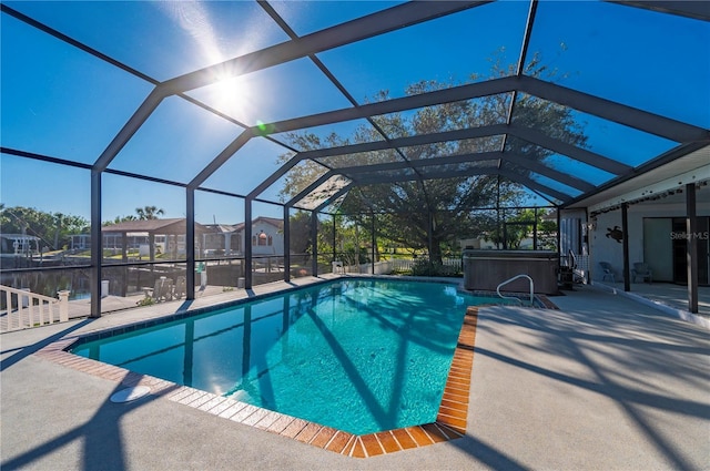 view of swimming pool with a hot tub, a water view, glass enclosure, and a patio area