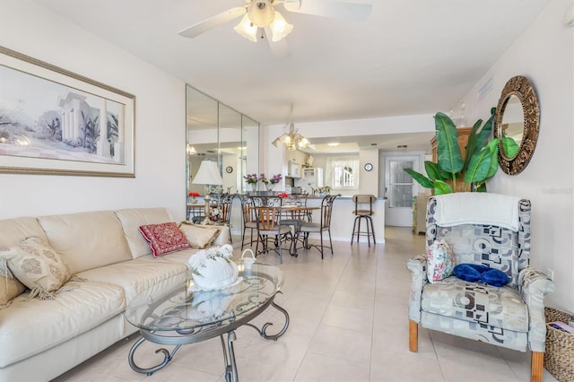 tiled living room with ceiling fan with notable chandelier