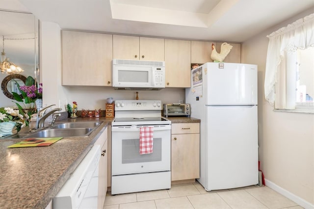 kitchen featuring white appliances, sink, light tile patterned floors, light brown cabinetry, and a tray ceiling