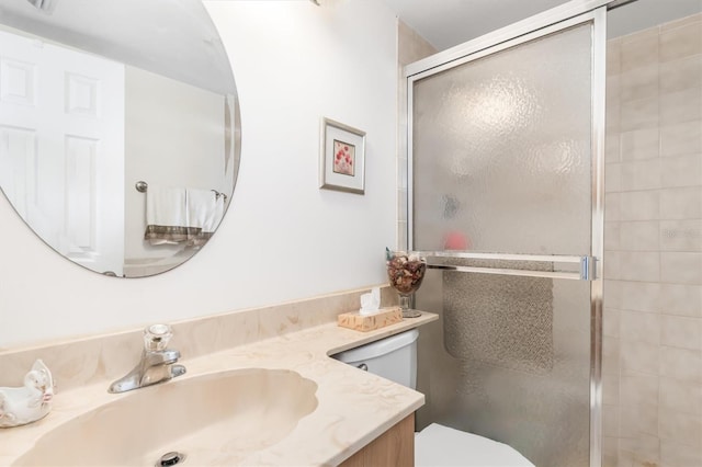 bathroom with vanity, toilet, and a shower with door