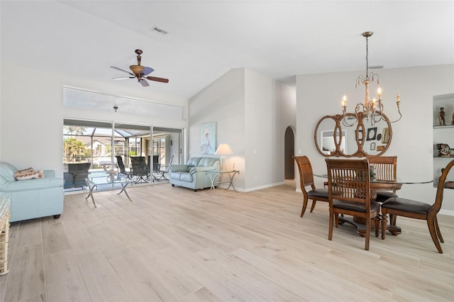 dining space featuring ceiling fan with notable chandelier, light wood-type flooring, and vaulted ceiling