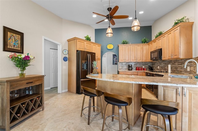 kitchen featuring light stone countertops, ceiling fan, sink, stainless steel fridge with ice dispenser, and hanging light fixtures