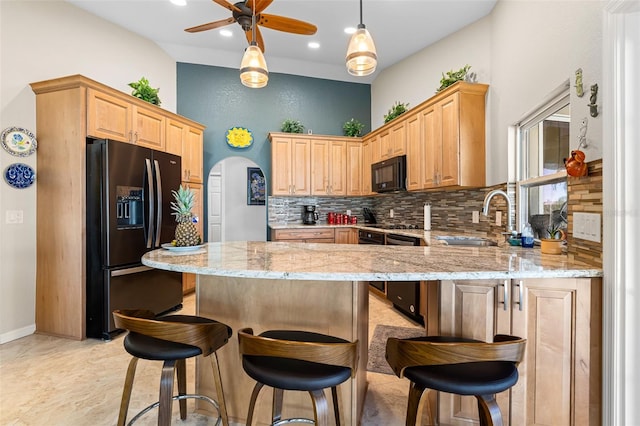 kitchen with ceiling fan, sink, light stone counters, backsplash, and black appliances