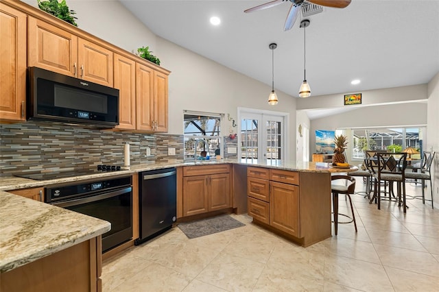 kitchen with a breakfast bar, black appliances, sink, light stone counters, and kitchen peninsula