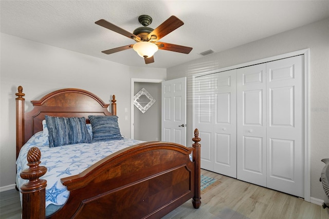 bedroom with a textured ceiling, a closet, light hardwood / wood-style flooring, and ceiling fan