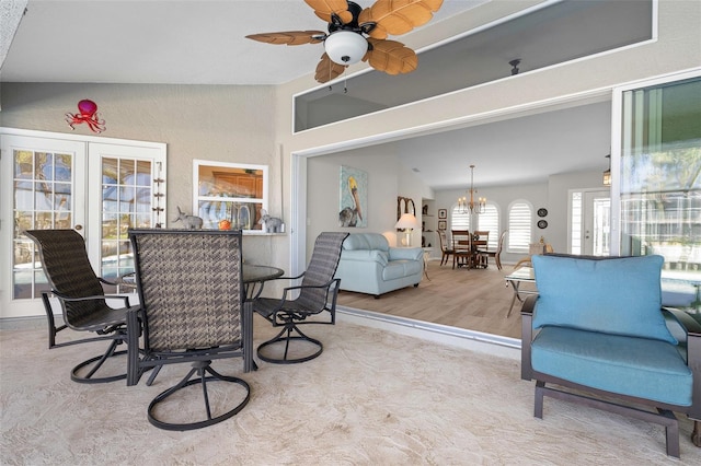 dining room featuring french doors, ceiling fan with notable chandelier, light hardwood / wood-style flooring, and lofted ceiling