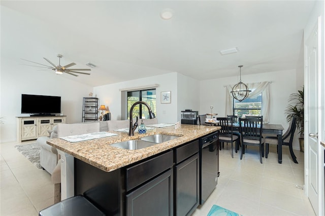 kitchen with a wealth of natural light, decorative light fixtures, sink, and a kitchen island with sink