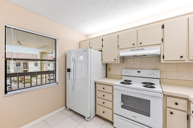 kitchen with decorative backsplash, white appliances, a textured ceiling, cream cabinets, and light tile patterned floors