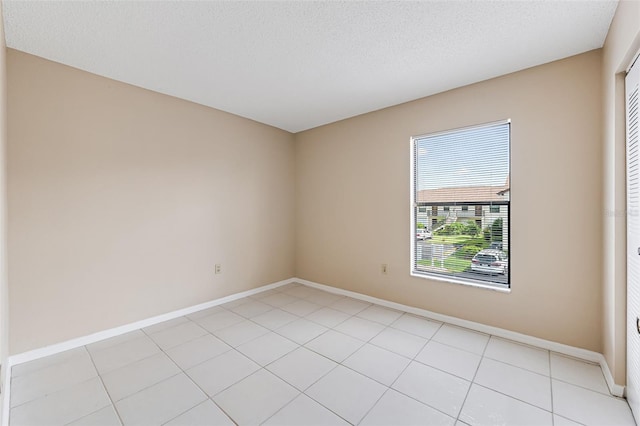 empty room featuring a textured ceiling and light tile patterned flooring