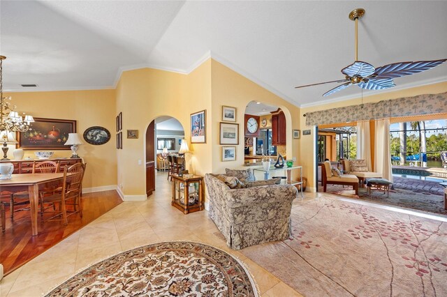 living room featuring lofted ceiling, crown molding, light hardwood / wood-style floors, and ceiling fan with notable chandelier