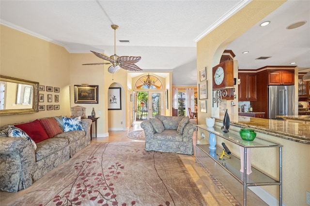 living room with a textured ceiling, ceiling fan, light tile patterned floors, and crown molding