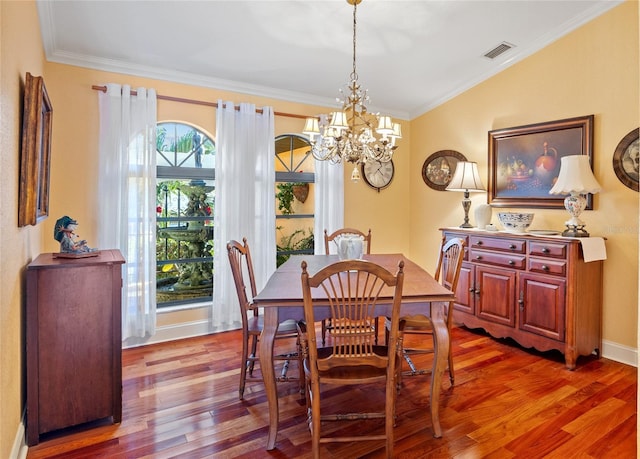 dining area with wood-type flooring, crown molding, and an inviting chandelier