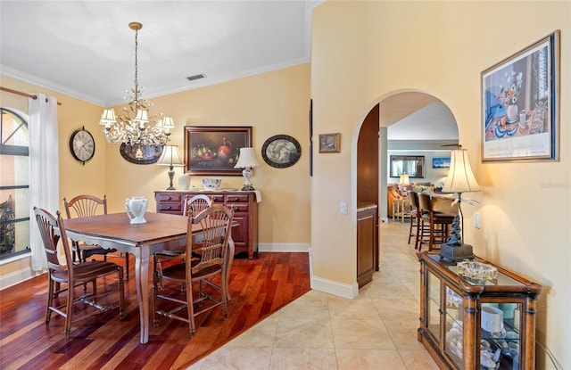 dining space with crown molding, light hardwood / wood-style floors, lofted ceiling, and an inviting chandelier