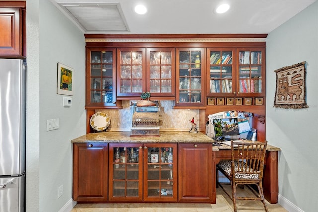 bar with tasteful backsplash, stainless steel fridge, light tile patterned floors, and light stone counters