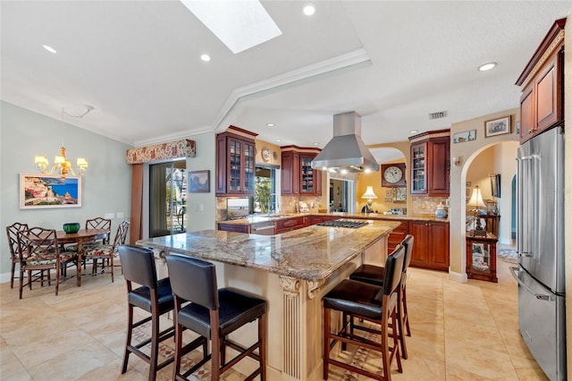 kitchen with a center island, a skylight, appliances with stainless steel finishes, tasteful backsplash, and island range hood