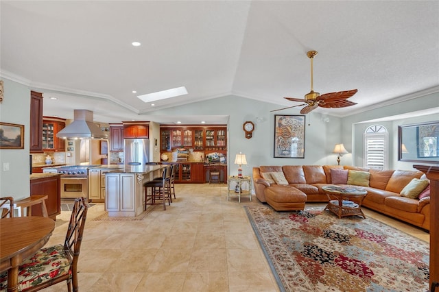 living room featuring crown molding, ceiling fan, light tile patterned flooring, and lofted ceiling with skylight