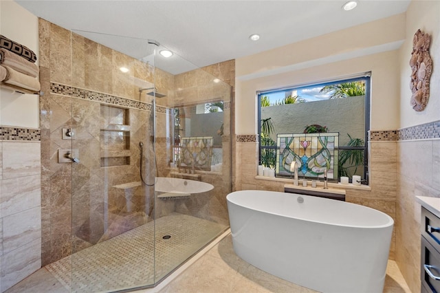 bathroom featuring plus walk in shower, vanity, tile patterned floors, and tile walls