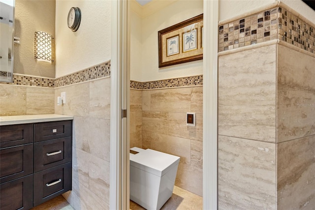 bathroom featuring vanity, tile walls, and toilet