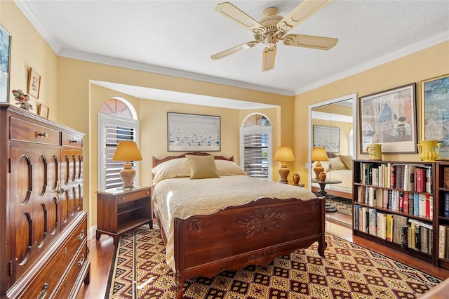 bedroom featuring a textured ceiling, ceiling fan, hardwood / wood-style flooring, and ornamental molding