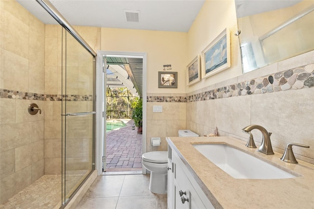 bathroom featuring walk in shower, tile patterned flooring, toilet, vanity, and tile walls