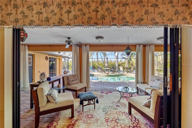 sitting room with ceiling fan, a textured ceiling, and a swimming pool