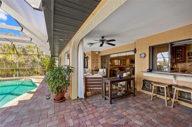 view of patio featuring ceiling fan and glass enclosure